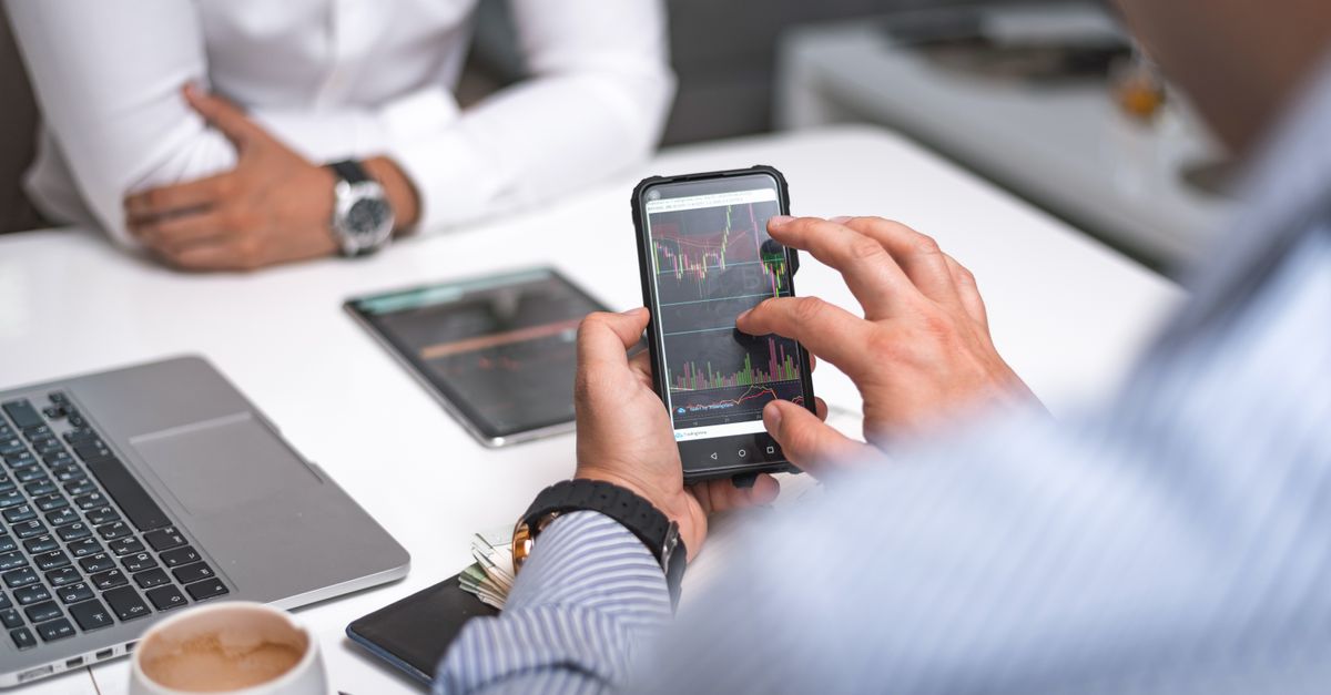 Business professionals using smartphone for data analysis in a modern office setting.